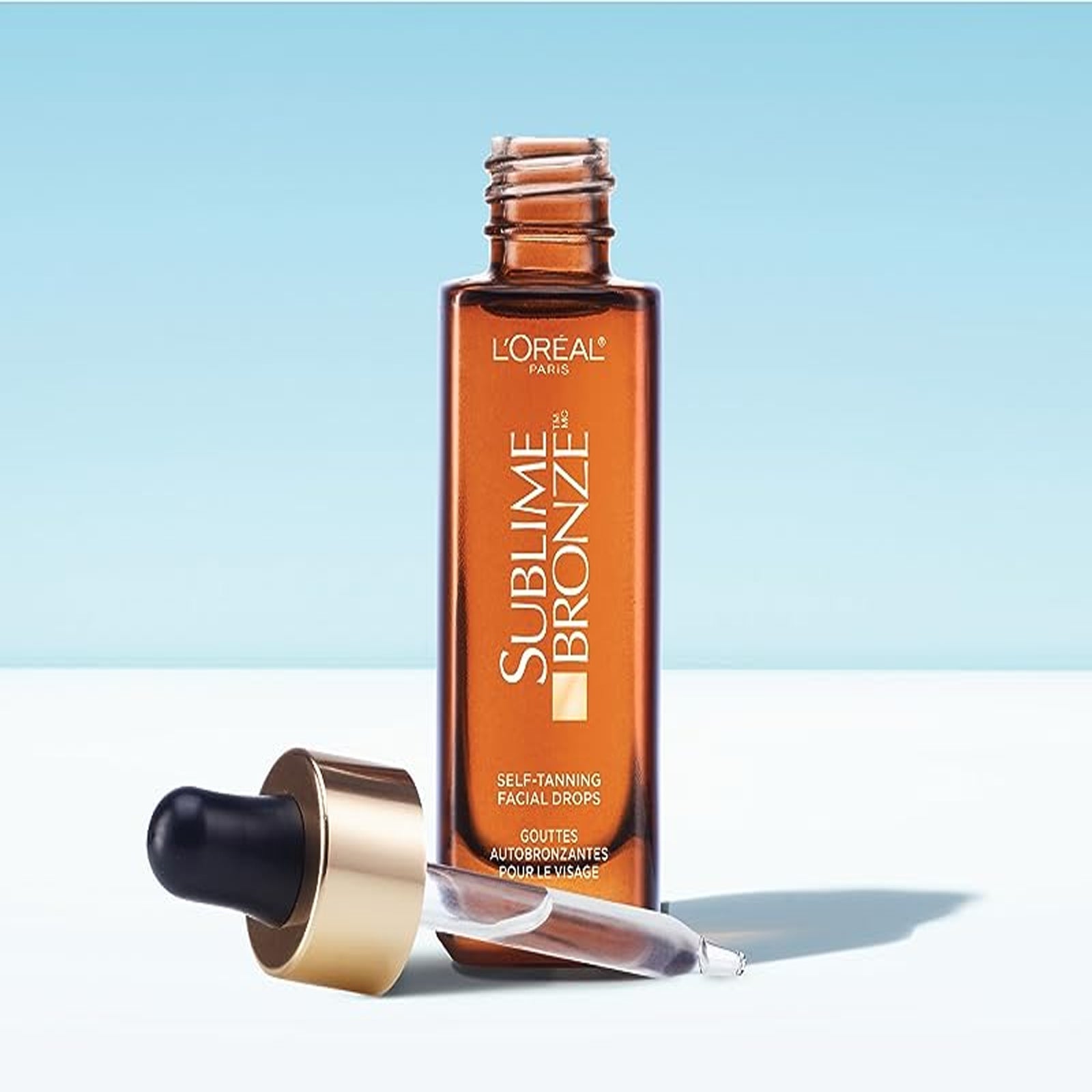 Bottle of L'Oreal Paris Sublime Bronze Self-Tanning Facial Drops, surrounded by hydrating ingredients.